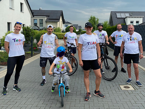 Muko-Spendenlauf 2021 - Gruppenbild Team Wahle: 7 Erwachsene und ein Kind auf dem Fahrrad, alle tragen selbstgemalte T-Schirts mit dem Teamnamen