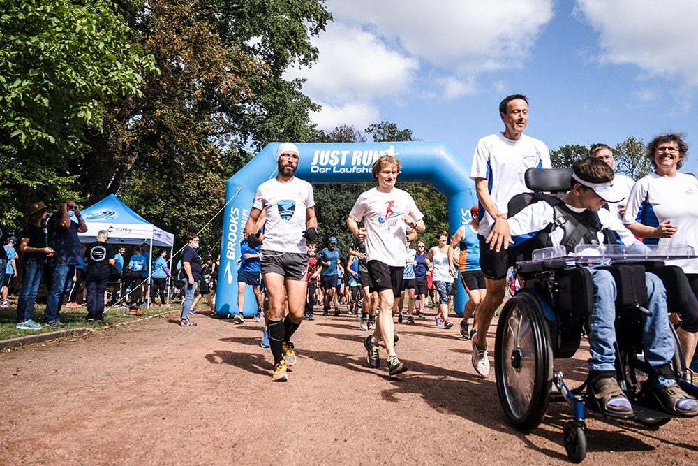 Foto Muko-Spendenlauf Hannover: verschiedene Läufer*innen, ein Rollstuhlfahrer wird geschoben